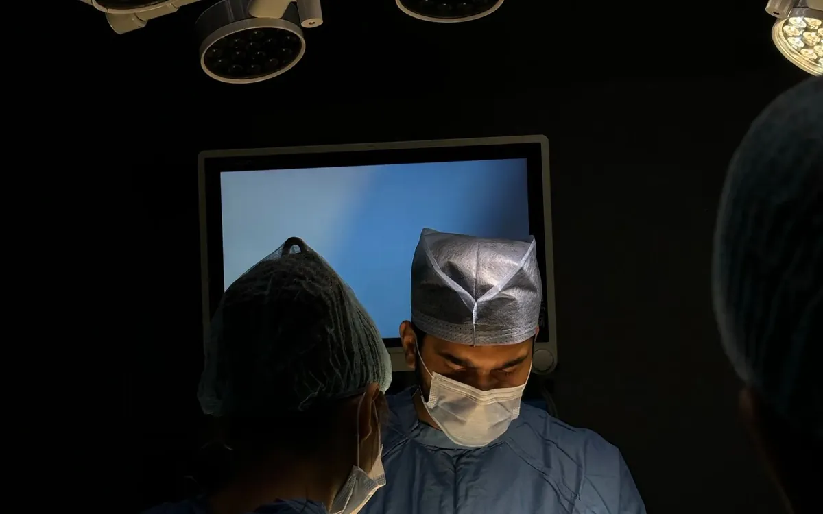 Ästhetisches Chirurgenteam bei der Arbeit unter Operationsleuchten in einem modernen Operationssaal